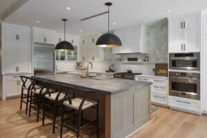 remodel of large kitchen, with white cabinents and large island with hanging lights